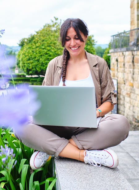 A woman using her laptop and smiling outdoors