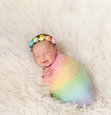 A baby with a rainbow blanket and headband